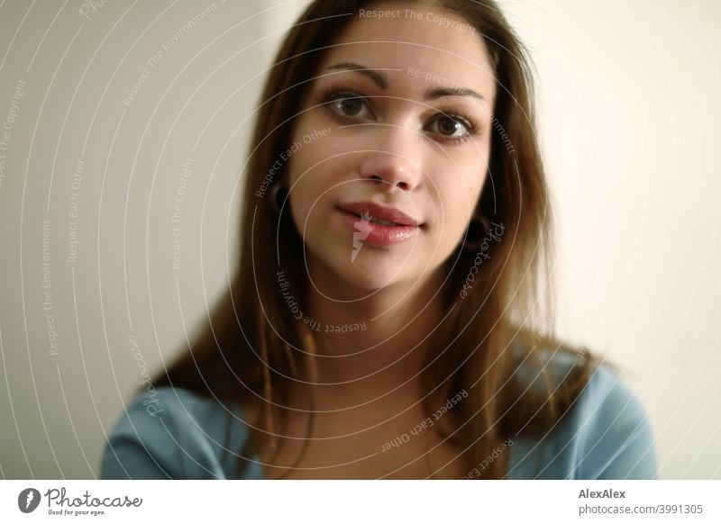 Portrait of a young brunette woman with a light blue top in a bright room Young woman pretty Brunette Long-haired Slim Feminine teen 18-25 years