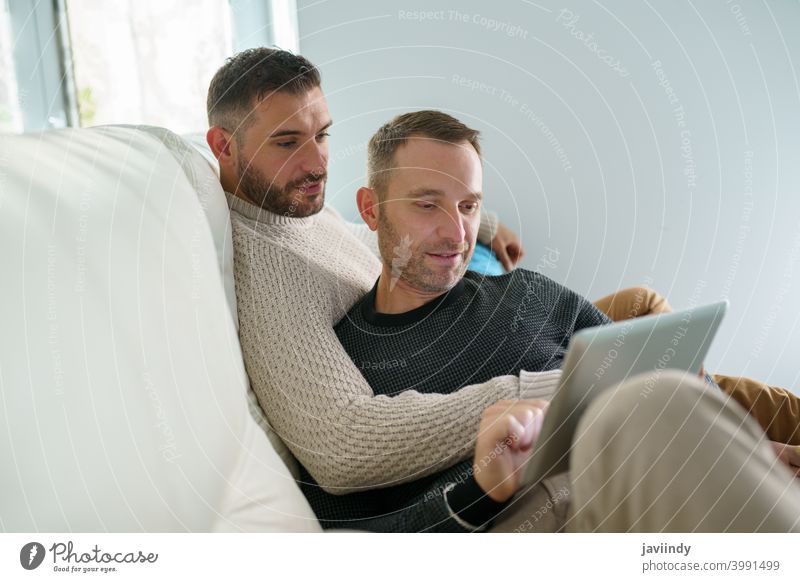 Gay couple consulting their travel plans together with a digital tablet. gay men homosexual lgbt lgbtq male relationship boyfriend people 30s togetherness man