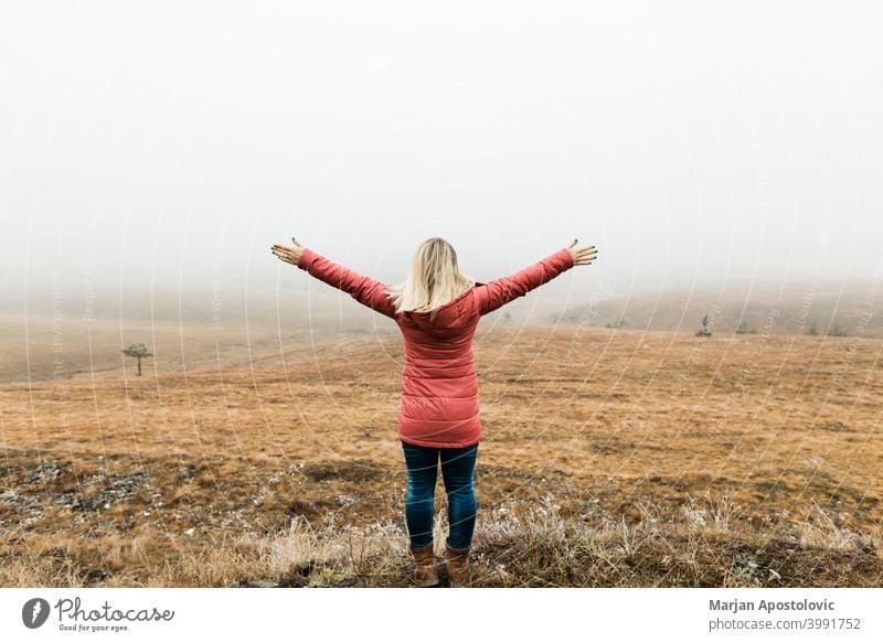 Young woman exploring nature on a foggy winter morning adventure autumn cloud cold countryside discovery exploration explore explorer female field freedom grass