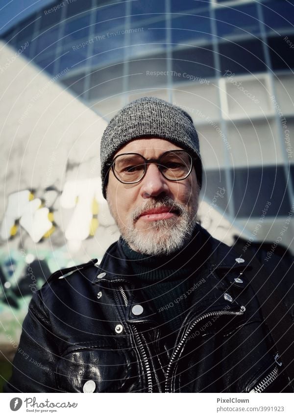 Man with glasses and cap in front of a building Only one man portrait 1 Person Adults Face of a man Head Facial hair Eyeglasses Cap