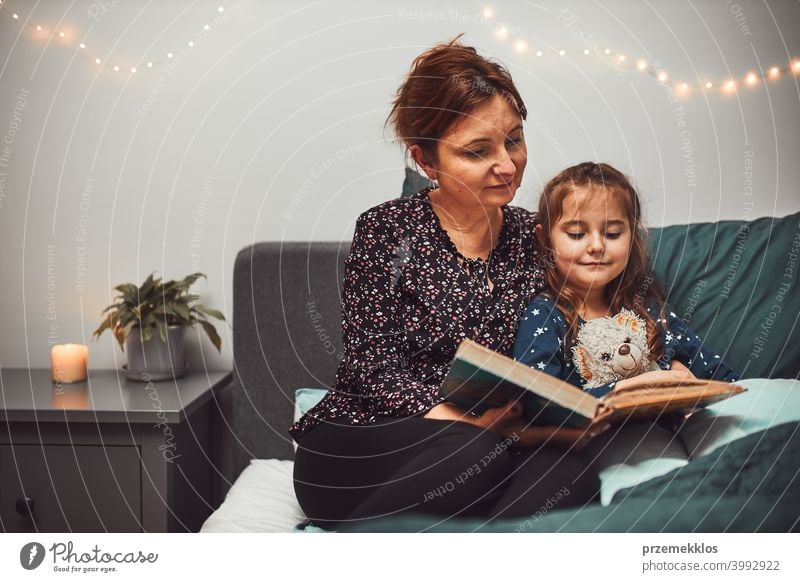 Mother reading book her daughter in bed before going to sleep. Bedtime stories for child night mother bedtime family home literature woman bedroom fairy parent