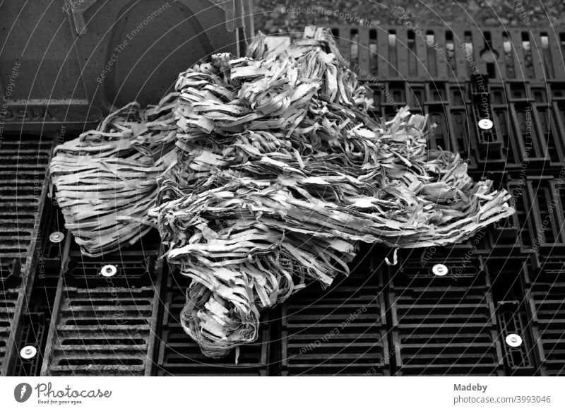 Paper balls made of paper strips on gridded pallets on a construction site in the capital Berlin, photographed in classic black and white waste Trash