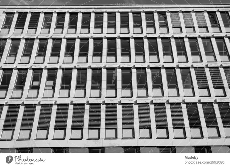 Office building with narrow windows and blinds as sun protection in summer sunshine in the West End of Frankfurt am Main in Hesse, photographed in classic black and white