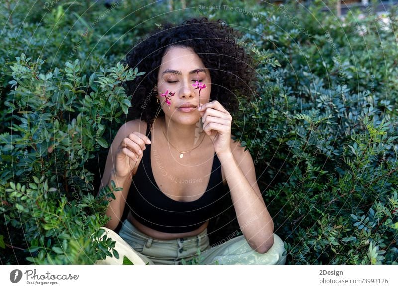 Outdoor fashion photo of beautiful young woman surrounded by plants flower beauty summer curly female girl portrait face hair model cute lifestyle outdoor enjoy