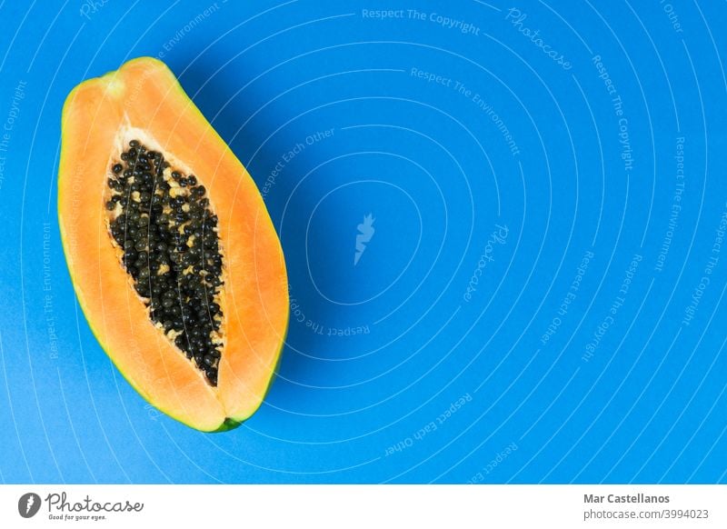 Papaya cut in half on blue background. Copy space. fruit carica carica papaya tropical seeds ripe sweet food dessert delicious juicy tasty top view copy space