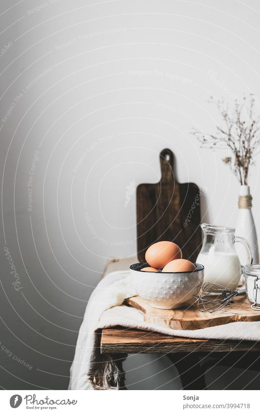 Brown eggs and baking ingredients on a kitchen table. Rustic style. Breakfast Wooden table rural scene Milk Flour Linen cloth Beige Bowl Food Interior shot