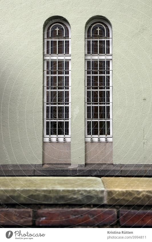 view over the monastery wall to two barred chapel windows Window latticed window grilles Grating Crucifix Crosses monastery windows Church window Monastery