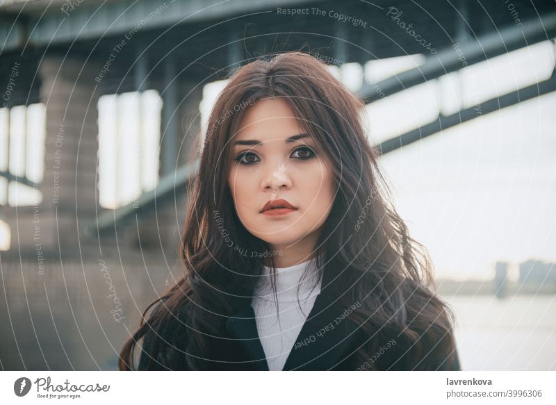 Portrait of asian woman in front of the bridge in cold fair weather girl female diversity portrait pretty coat hair outdoors alone autumn fall winter seasonal