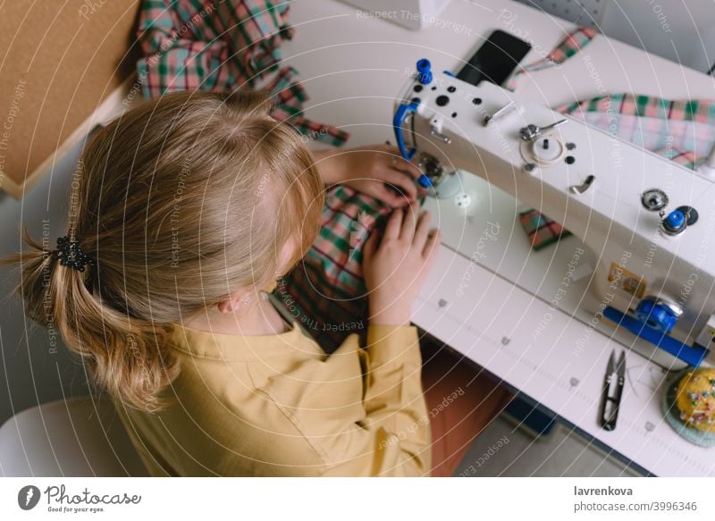 Top view of woman working with sewing machine in her workshop fabric tailor material seamstress clothing needle craft thread textile business worker dress