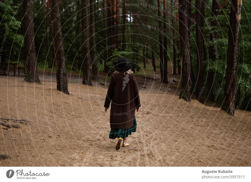 Woman walking in the forest on a cloudy autumns day Autumn leaves Coat Hat Autumn of life Autumnal weather Forest walk Forest path Rainy weather pure air