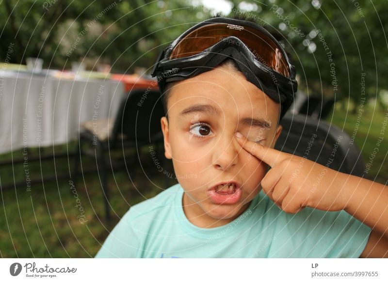 Child making a face and holding his finger on his eye hesitant puzzled Perplexed sceptical doubts doubtful Doubt hestitate uncertainty confusion Infancy reality