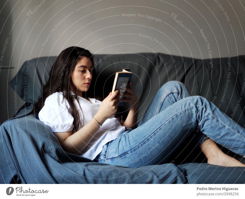 Woman reading on a sofa in a house home leisure sitting comfortable living room caucasian lifestyle brunette indoor domestic life casual attire happy woman