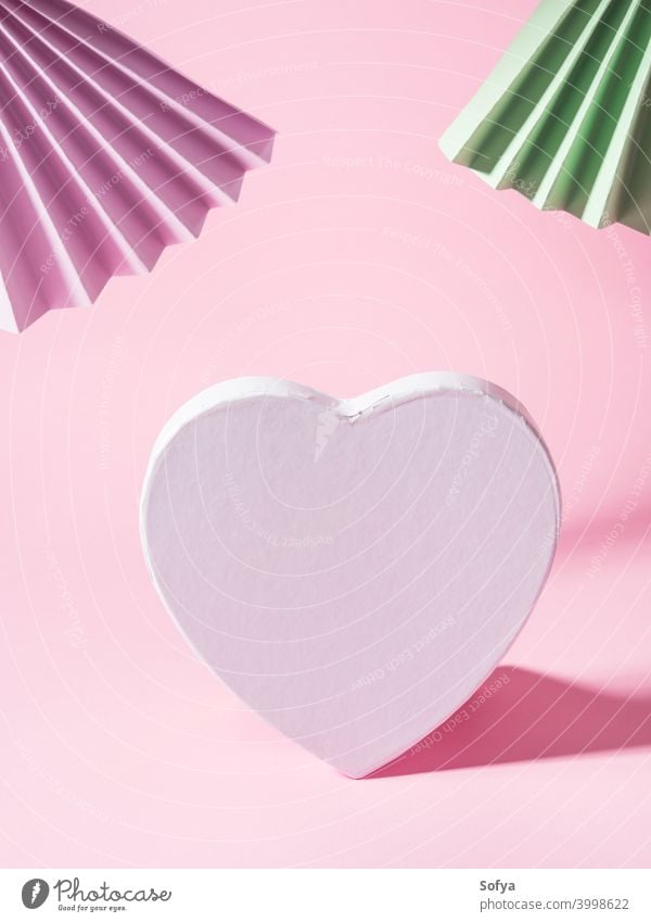 Geometrical pink background with paper fans and blank white heart shape love valentine day text invitation geometry holiday display bright mock up fashion