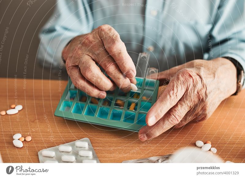 Senior man organizing his medication into pill dispenser. Senior man taking pills from box senior disease patient prescription medical medicine person