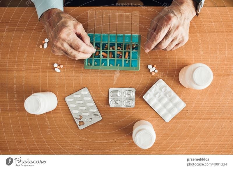 Senior man organizing his medication into pill dispenser. Senior man taking pills from box senior disease patient prescription medical medicine person