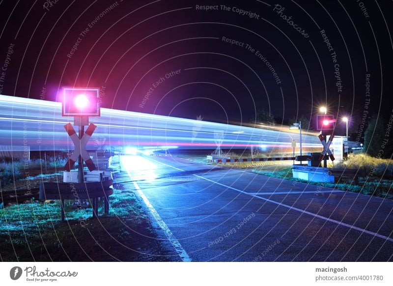 Night shot of a level crossing with passing train German Railway Railroad crossing Train travel Rail transport Deserted reflections Public transport