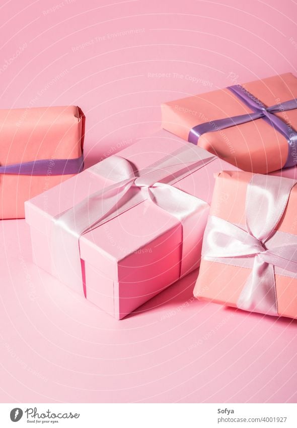 Pink wrapped gift boxes with ribbons on monochrome background baby shower pink valentine day mother birthday anniversary pastel satin present minimal stack