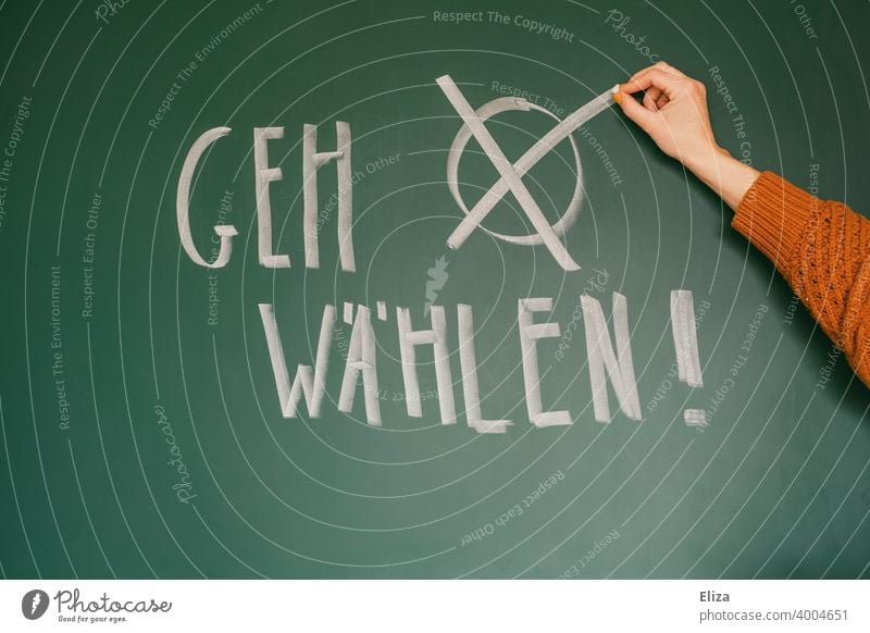 Prompt "Go vote!" written on a blackboard. Hand makes a cross. Federal elections. Elections Select Democracy Crucifix Vote German federal elections policy