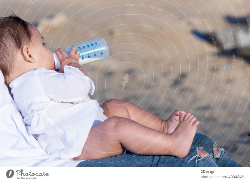 Newborn drinking milk from a baby bottle, sitting on mom legs outdoors newborn child infant mother healthy care cute person feeding childhood little white