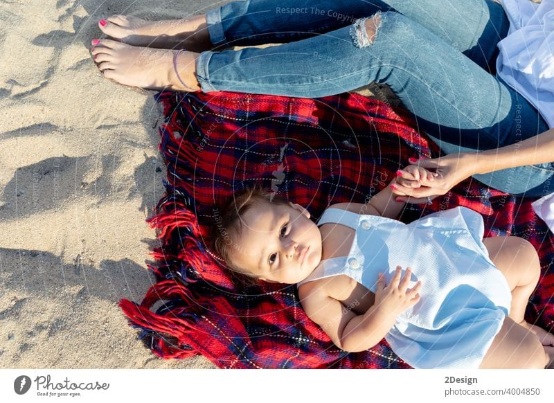 Smiling mom playing with newborn lying on beach towel baby love mother family happiness woman person smiling laughing sand sunlight together happy little summer