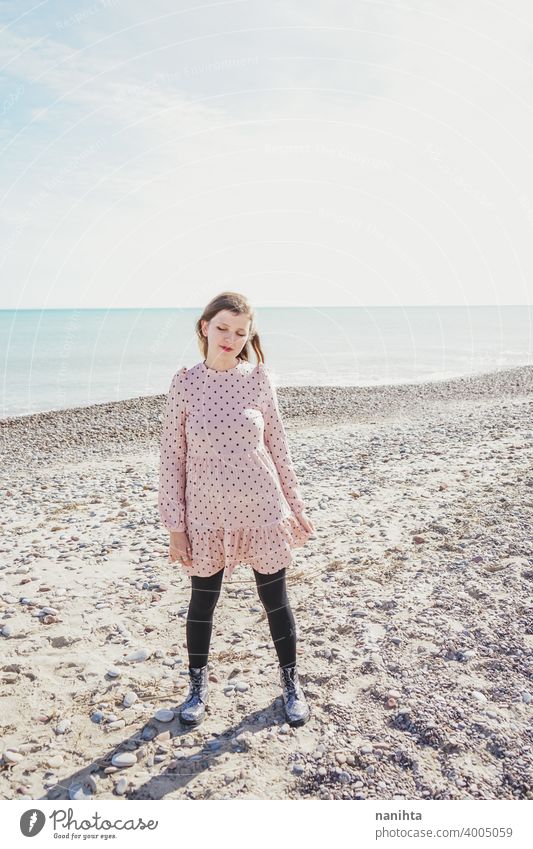 Young woman wearing a pink dress at the beach holidays trendy kawaii casual lifestyle blonde natural beauty attractive pretty fashion model wind windy sea shore