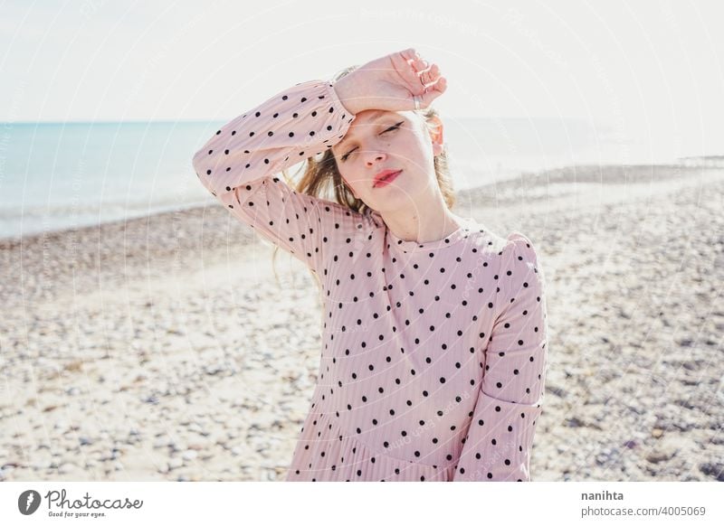 Young woman wearing a pink dress at the beach holidays trendy kawaii casual lifestyle blonde natural beauty attractive pretty fashion model wind windy sea shore