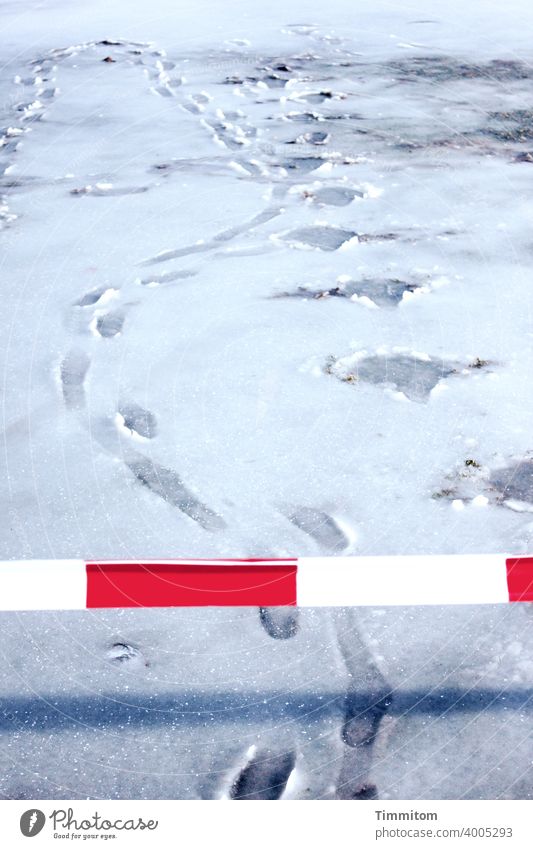 A barrier and footprints in the slush barrier tape cordon Red White Shadow Winter Cold Snow Snow mud Transgressions Tracks Deserted flutterband Exterior shot