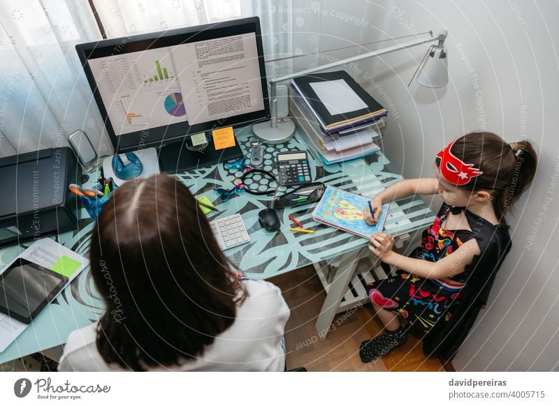 Woman teleworking with her daughter drawing overhead woman coronavirus covid-19 quarantine confinement computer top view family work reconciliation epidemic