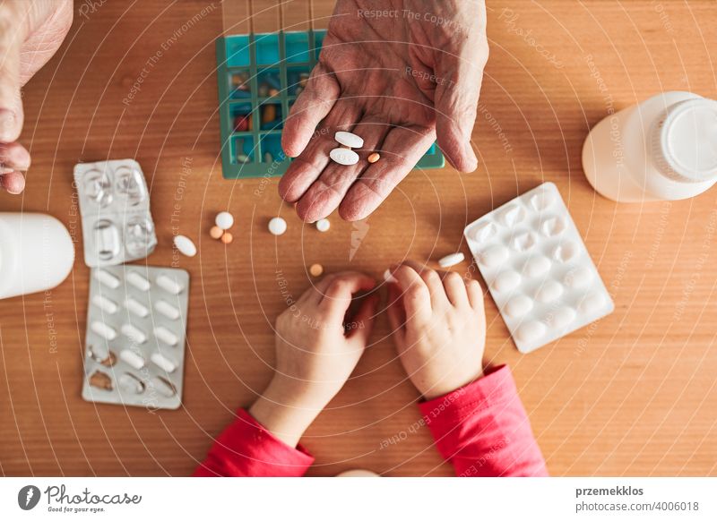 Grandchild helping grandfather to organize medication into pill dispenser. Senior man taking pills from box senior disease patient prescription medical medicine