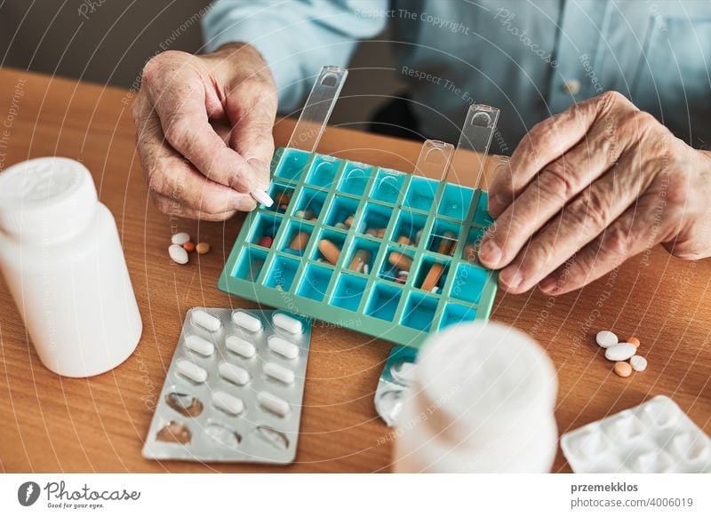 Senior man organizing his medication into pill dispenser. Senior man taking pills from box senior disease patient prescription medical medicine person