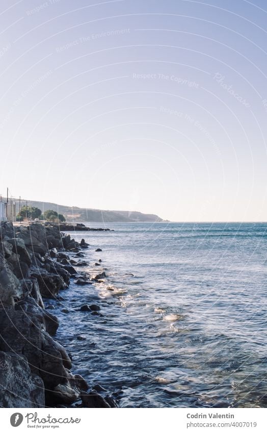 Coastline with small waves and rocks architecture bay beach boat body cliff cloud coast coastal and oceanic landforms dusk headland horizon lake landscape large