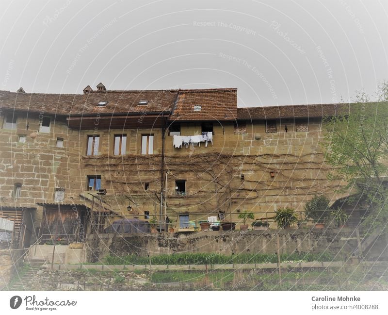 Alte Hausfassade mit Garten und Wäsche vor dem Fenster Fassade Idylle alt historisch architektur Architektur bauwesen haus Gebäude stein Himmel Natur Landschaft