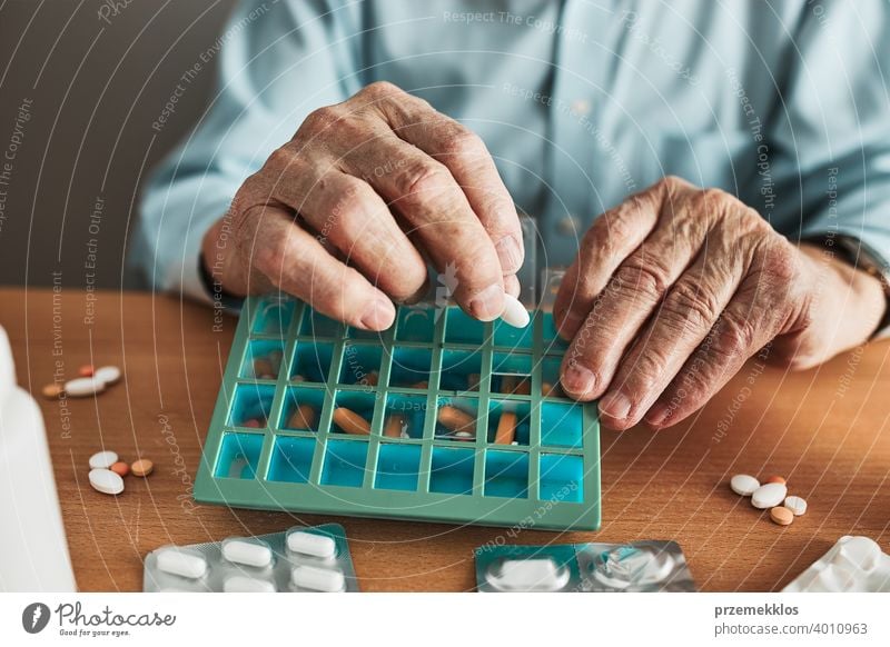 Senior man organizing his medication into pill dispenser. Senior man taking pills from box senior disease patient prescription medical medicine person