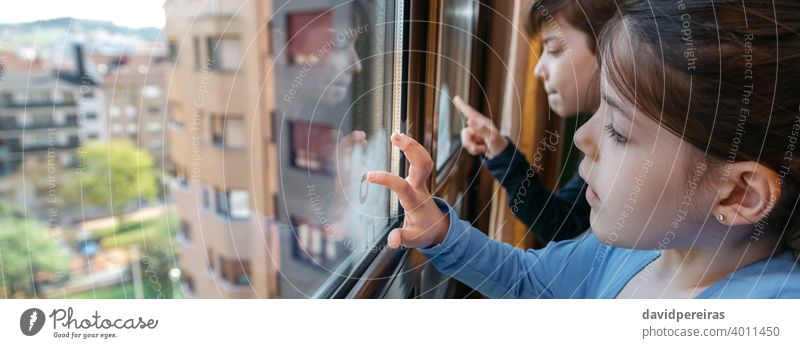 Two children in coronavirus lockdown drawing on the window covid-19 writing with finger panoramic copy space panorama quarantine banner playing header web home