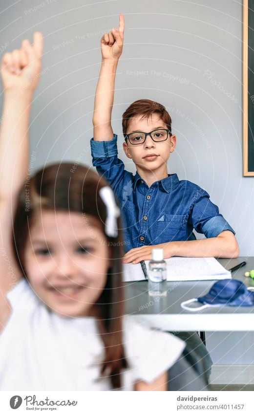 Students with mask on table raising hands at school coronavirus student boy class new normal participating safety people girl epidemic education classroom smart