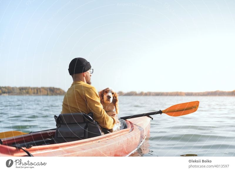 Man with a dog in a canoe on the lake. Young male person with spaniel in a kayak row boat, active free time with pets, companionship, adventure dogs 25-35 years