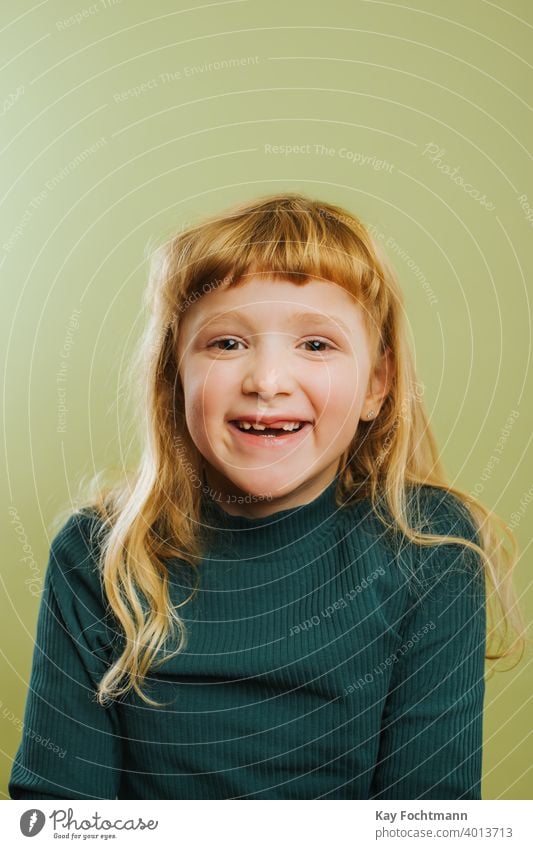 portrait of laughing blonde girl against green background bangs blond hair casual clothing child childhood colored background cute daughter emotion front view