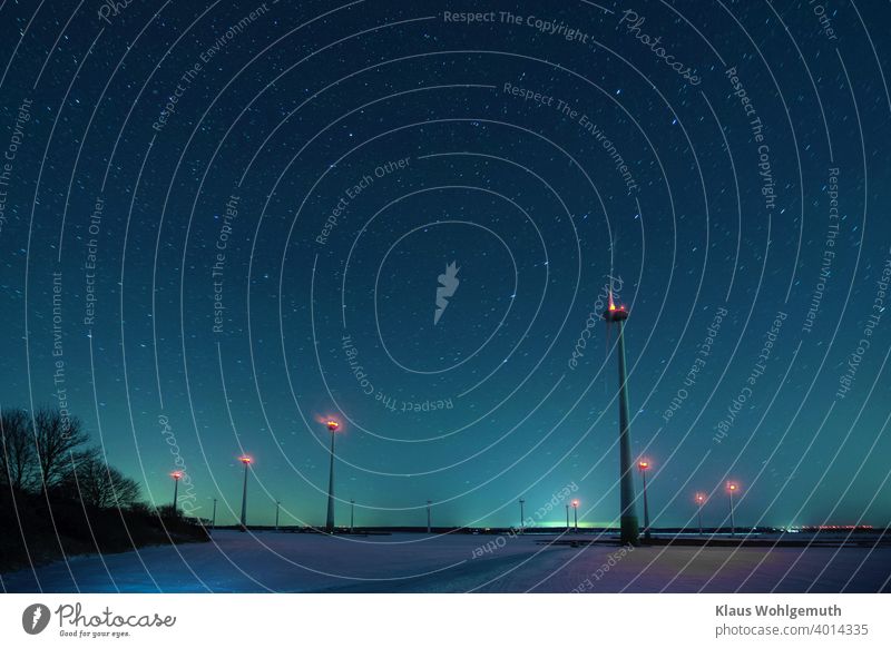 Winter night with starry sky above wind turbines on a snow-covered field Night Starry sky Big car windmills Snow Frost Long exposure Field Plain position lights