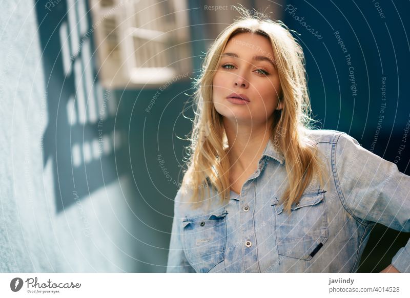 Portrait of blonde woman wearing denim shirt standing in the street. girl female russian blue eyes portrait fashion outdoors lady hairstyle person white pretty