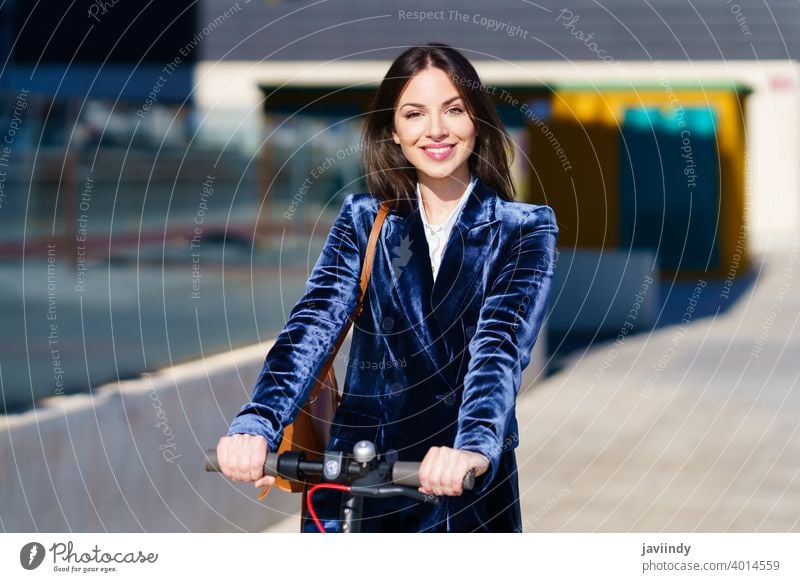 Young business woman wearing blue suit using electric scooter. businesswoman e-scooter girl urban vehicle street caucasian technology ride lifestyle city modern