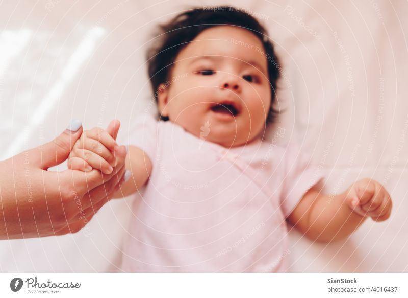 Mother is holding her daughter 's hand baby mother newborn hands love care white child mom family young woman people kid childhood small little infant finger