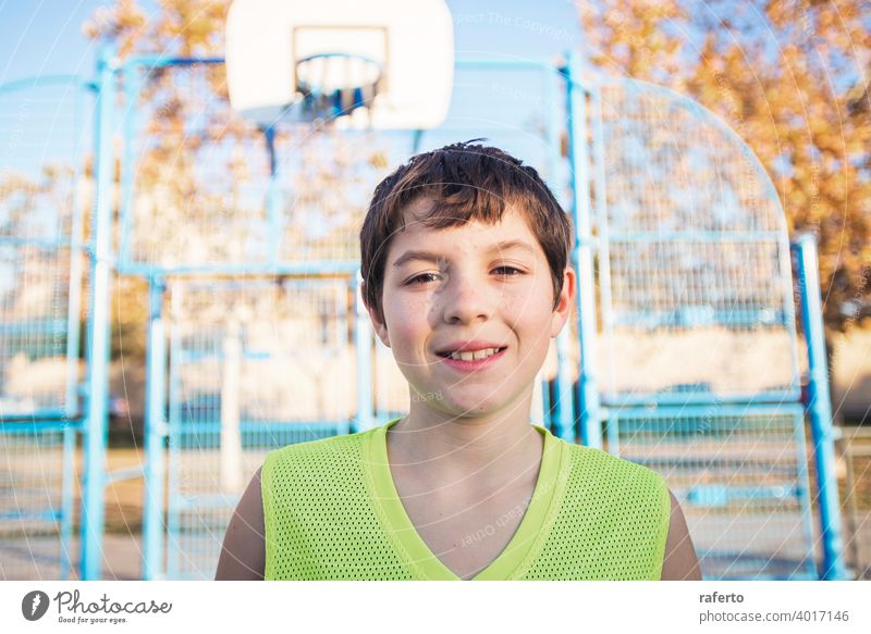 Portrait of a young teen male with sleeveless standing on a street basket court while smiling at camera basketball player real teenage youth boy fit happy game