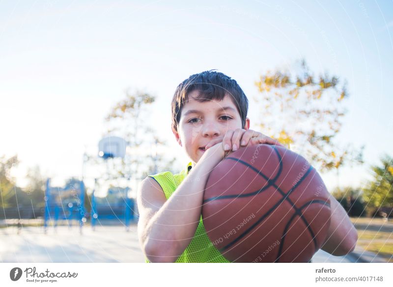 Portrait of a young teen male with sleeveless standing on a street basket court while smiling at camera basketball player real teenage youth boy fit happy game