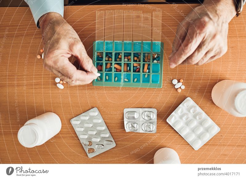 Senior man organizing his medication into pill dispenser. Senior man taking pills from box senior disease patient prescription medical medicine person