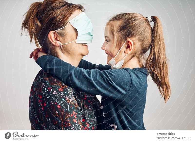 Little girl kissing her mother who has covered eyes with face mask for fun daughter child family woman love care together lifestyles protection healthy