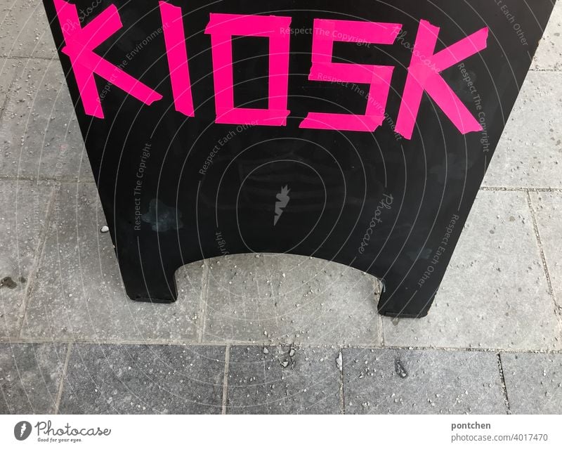 Kiosk is written in neon, pink, on a sign in front of a store. display Letters (alphabet) sale Sell Advertising Characters Signs and labeling Typography