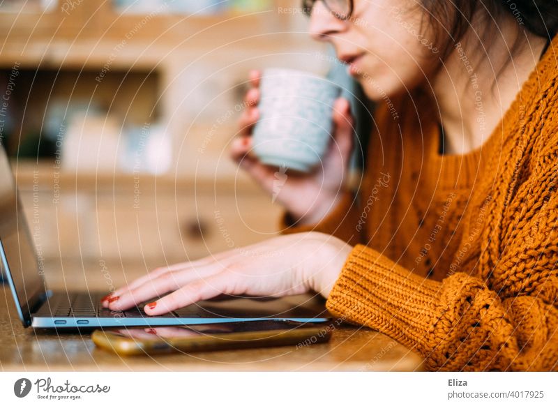 A woman sits at the table with coffee and laptop at home and works in the home office Home Office labour Coffee cup Notebook Computer Workplace Business