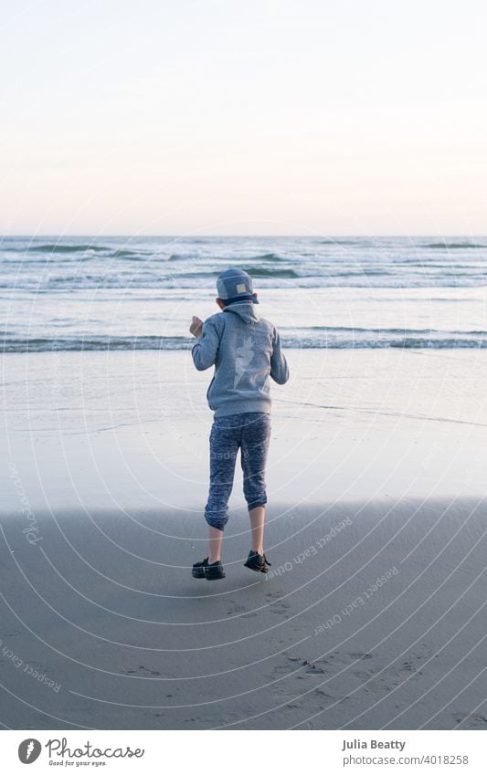 Child with Autism jumping in mid air out of joy; background is a beach with waves stop motion Freeze happy boy child childhood kid blue gray sand tide wet cool