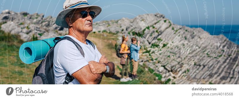 Senior man trekking looking at the landscape hikers senior retired nature hat sunglasses banner web header panoramic panorama countryside summer mountain