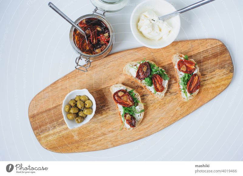 italian traditional bruschetta - bread toast with sun dried tomatoes, cream cheese, olive oil and arugula. sandwich food snack vegetable healthy herb appetizer